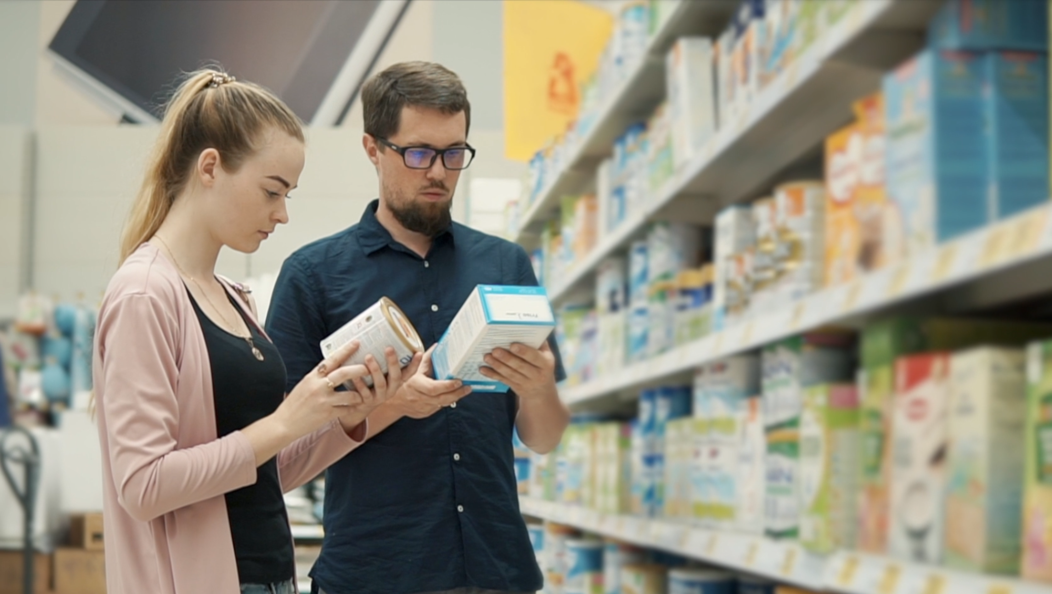 parents looking at baby formula ingredients in a grocery store