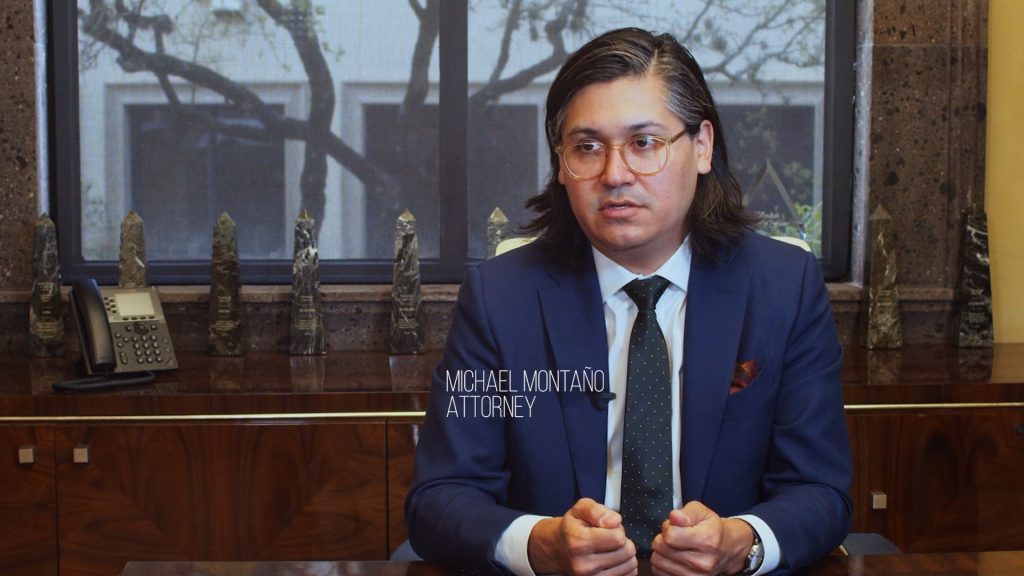 man with long hair in a suit and glasses being interviewed - Michael Montano